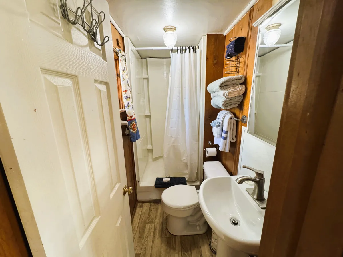 A well-maintained full bathroom with a modern shower area, a spotless sink, and neatly arranged towels on a rack. The bathroom is compact but thoughtfully designed, providing privacy and all the essentials for personal grooming and relaxation after an active day.